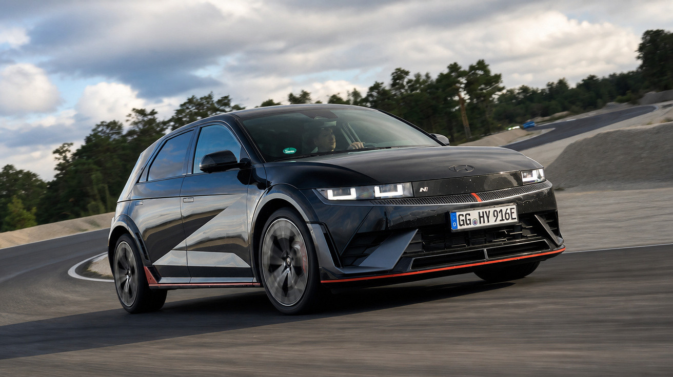Carro preto esportivo Hyundai i20 N em curva rápida em pista de corrida sob céu nublado.