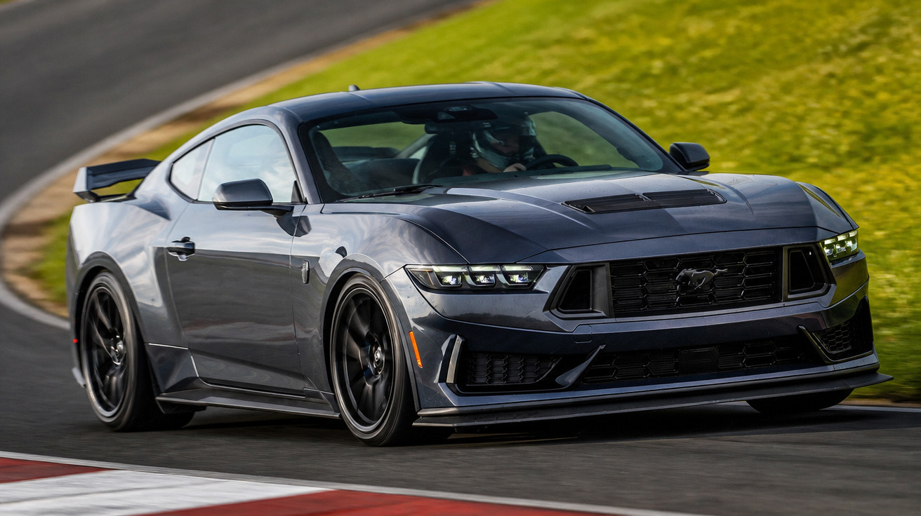 Carro esportivo cinza escuro Ford Mustang em alta velocidade numa pista de corrida.