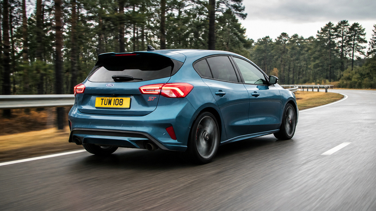 Carro hatchback azul Ford ST trafegando em estrada molhada com árvores ao fundo.