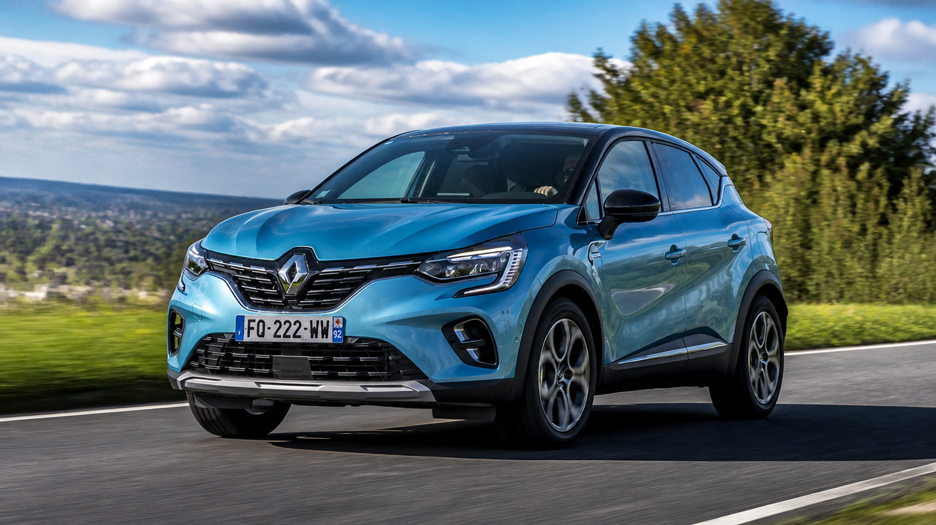 Carro Renault azul em movimento em estrada com céu azul e árvores ao fundo.