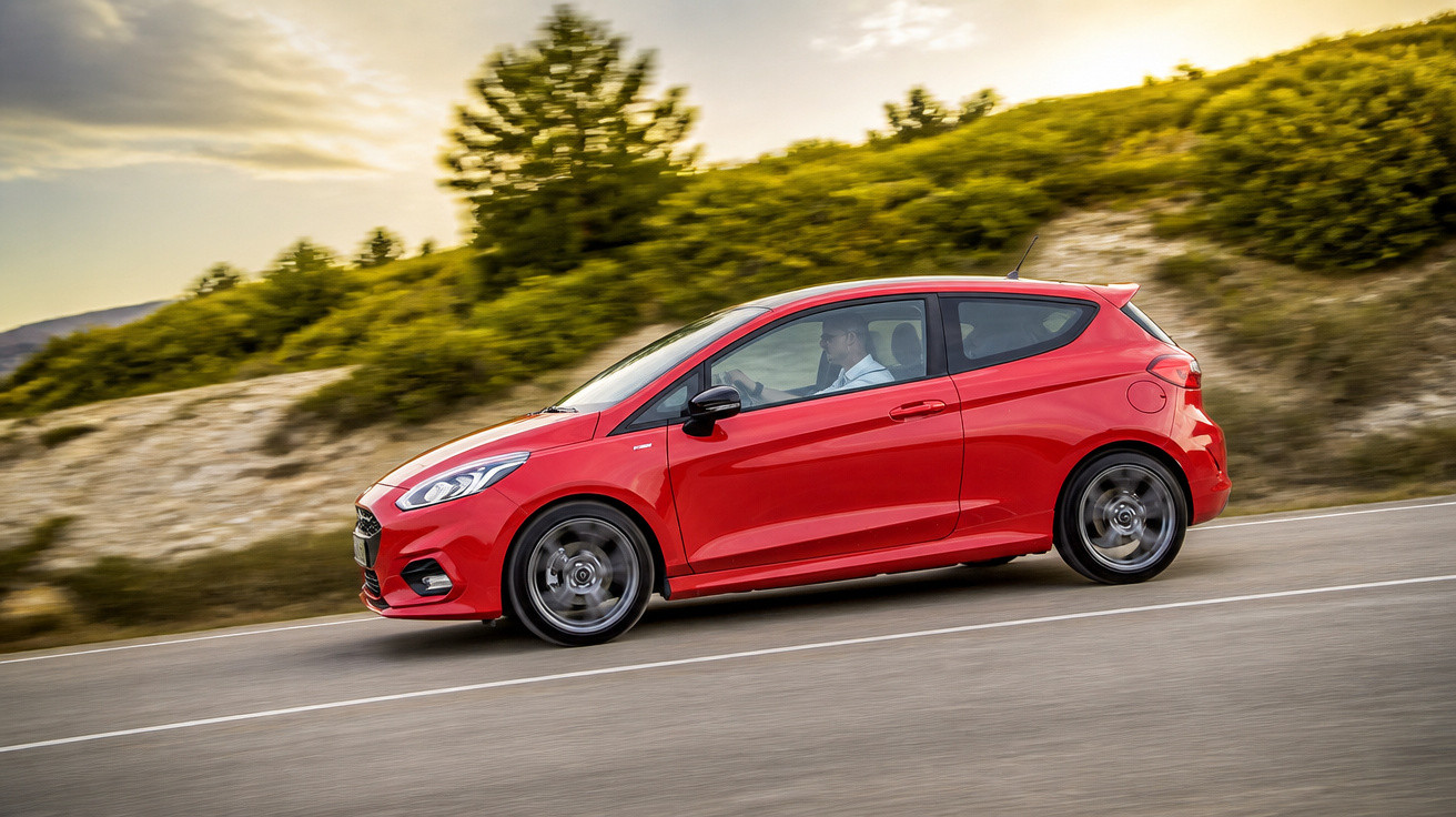 Carro esportivo vermelho em movimento, dirigindo por estrada sinuosa com vegetação ao fundo.