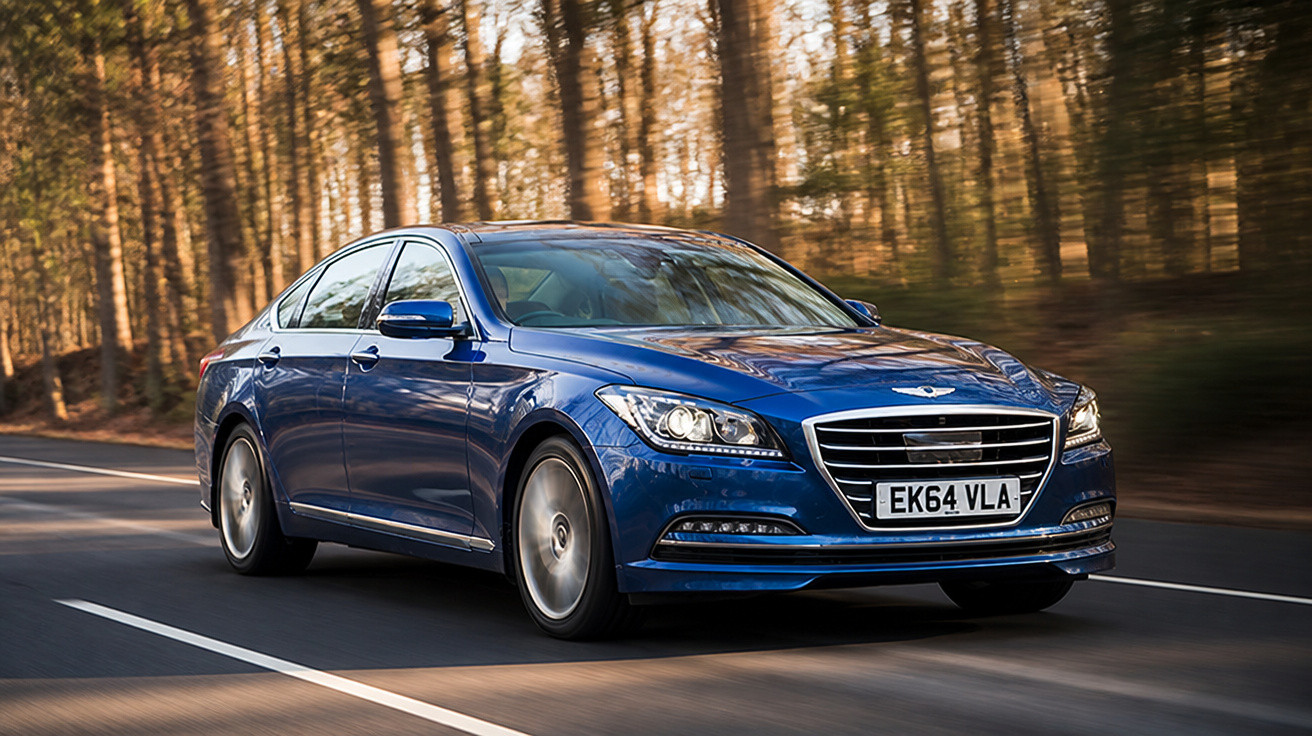 Carro sedan azul em movimento numa estrada cercada por árvores ao entardecer.
