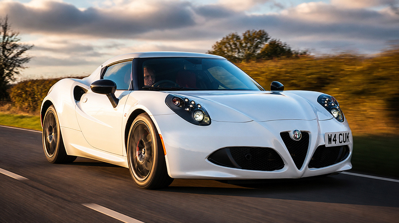 Carro esportivo branco Alfa Romeo 4C em movimento em estrada com paisagem ao fundo.