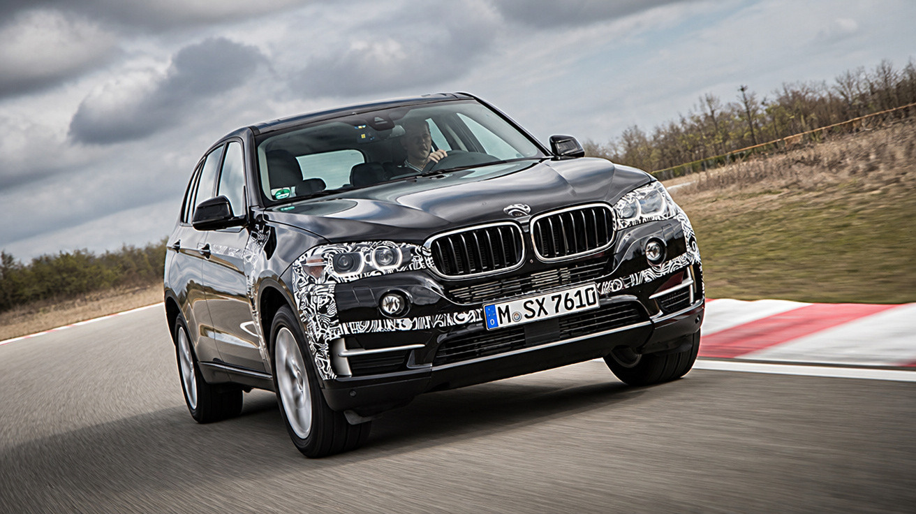 Carro preto BMW SUV no asfalto, tirado em ângulo de frente durante uma curva em pista de corrida.